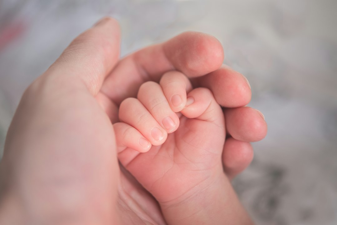 Close-up of a parent's hand holding a newborn baby's hand