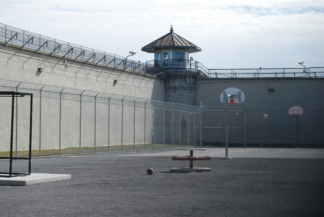 A prison yard surrounded by fencing and razor wire
